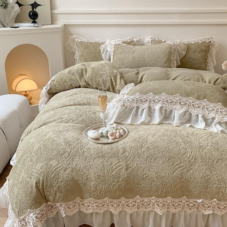 Pode incluir: Uma cama com um edredom com estampa floral verde s&aacute;lvia e fronhas combinando. A roupa de cama tem acabamento em renda branca. Uma bandeja de prata com uma vela e flores est&aacute; sobre o edredom. Um copo de champanhe tamb&eacute;m est&aacute; na bandeja.