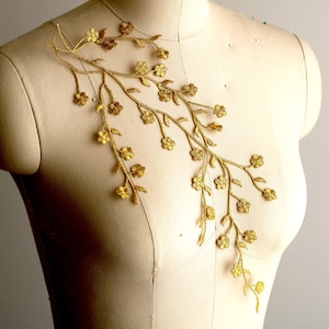 May include: Gold floral applique with delicate branches and small flower details. This embellishment is perfect for adding a touch of elegance to clothing, accessories, or home decor projects.
