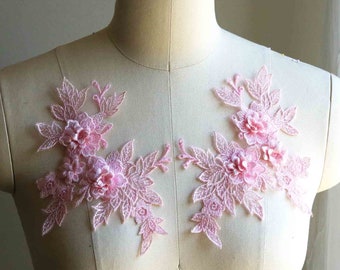 May include: Two delicate pink floral lace appliques with 3D flowers. The appliques are perfect for adding a touch of elegance to clothing, accessories, or home decor projects.