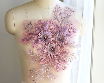 Puede incluir: Una aplicación floral rosa y plateada con pedrería. La aplicación está en un maniquí blanco.