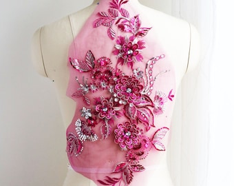 May include: A pink floral applique with sequins and rhinestones on a sheer pink fabric. The applique is perfect for adding a touch of elegance to any garment.