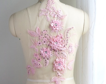 May include: Pink floral lace applique with rhinestones. The applique features delicate flowers and leaves, perfect for adding a touch of elegance to any garment.