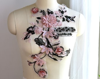 May include: A delicate floral applique with pink and black flowers, leaves, and beads. The applique is on a white mannequin.
