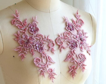 Puede incluir: Dos aplicaciones de encaje floral de color rosa con detalles de cuentas. Las aplicaciones están en un maniquí blanco.
