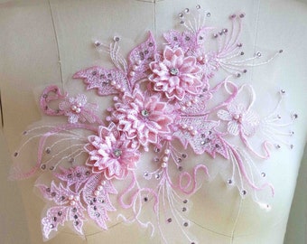 Puede incluir: Aplique floral rosa con adornos de perlas y diamantes de imitación sobre una tela de malla blanca. Esta delicada aplicación es perfecta para agregar un toque de elegancia a la ropa, los accesorios o la decoración del hogar.