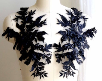 Puede incluir: Aplique de encaje floral negro con lentejuelas y cuentas. El aplique está en un maniquí de busto blanco.