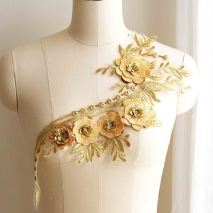 Puede incluir: Aplique floral dorado con delicadas hojas y detalles de cuentas. Esta decoración presenta un grupo de flores tridimensionales y es perfecta para agregar un toque de elegancia a la ropa o las manualidades.