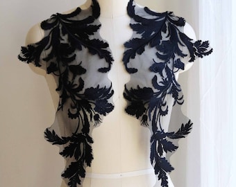 May include: Black lace applique with a floral design. The applique is on a white dress form.