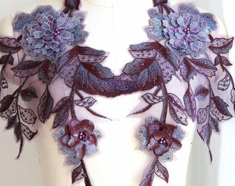 May include: A pair of purple and burgundy floral appliques with beaded accents. The appliques are made of lace and are perfect for adding a touch of elegance to any garment.