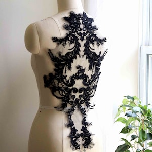 May include: Black lace applique with a floral design. The lace is delicate and intricate, and it would be perfect for adding a touch of elegance to a garment.