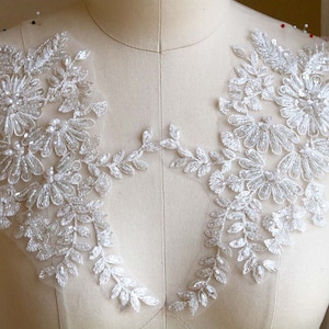 以下が含まれることがあります： 花柄と葉柄の白いビーズレースアップリケ。アップリケは、ウェディングドレス、ブライダルアクセサリー、その他のクラフトプロジェクトにエレガントなタッチを加えるのに最適です。