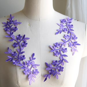 May include: Two pieces of purple floral lace applique with a delicate vine design. The lace is perfect for adding a touch of elegance to any project.
