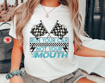Op de afbeelding: Wit T-shirt met een ontwerp van een blauw-zwarte geruite vlag. De tekst "Run your car not your mouth" is op het shirt gedrukt.