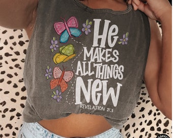 May include: A gray sleeveless shirt with the text "He makes all things new" and a Bible verse, "Revelation 21:5". The shirt features a colorful butterfly design.