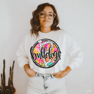 May include: White sweatshirt with a pink, black, and white floral design with the word "bulldogs" in black lettering.