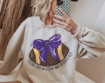 Può includere: Una felpa beige con una grafica di un pallone da calcio viola e giallo e il testo "Let the field be joyful and all fear is in you".