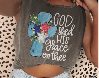 May include: A grey sleeveless shirt with a blue cross and stars in red, white and blue. The shirt has the text "God shed His grace on thee" printed on it.