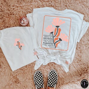 May include: White t-shirt with a floral design and the text "for everything there is a SEASON and a time for every PURPOSE under heaven. Ecclesiastes 3:1-8"