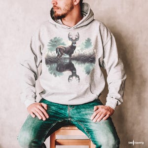 May include: A gray hooded sweatshirt with a print of a white-tailed deer standing in a lake with its reflection in the water.