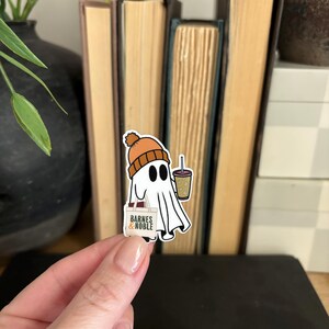May include: A white ghost wearing an orange beanie and holding a cup of coffee and a "Barnes & Noble" bag.