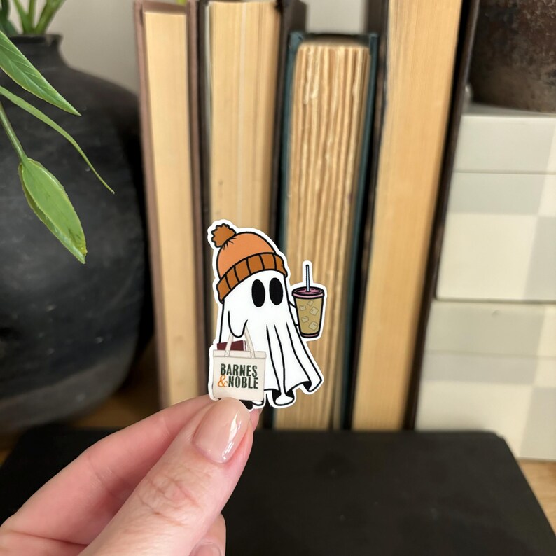 May include: A white ghost wearing an orange beanie and holding a cup of coffee and a "Barnes & Noble" bag.