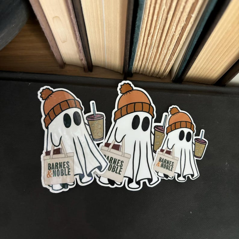 May include: Three white ghost stickers with orange knit hats holding brown cups and a bag with the text "Barnes & Noble" printed on it.