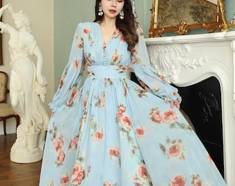 Puede incluir: Un vestido maxi azul claro con estampado floral. El vestido tiene mangas largas con puños fruncidos, un escote en V y una cintura ajustada.