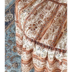 May include: A white ceramic mug with a black handle and the text "But First, Coffee" in a bold, black font. The mug is set against a blurred background, suggesting a cozy setting. The mug appears to be approximately 4 inches tall.