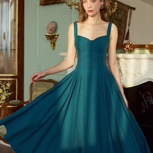 May include: A teal-colored dress with a sweetheart neckline and wide straps. The dress features a fitted bodice and a full, pleated skirt. The fabric appears to be a textured linen or similar material. The dress is a vintage or retro style.
