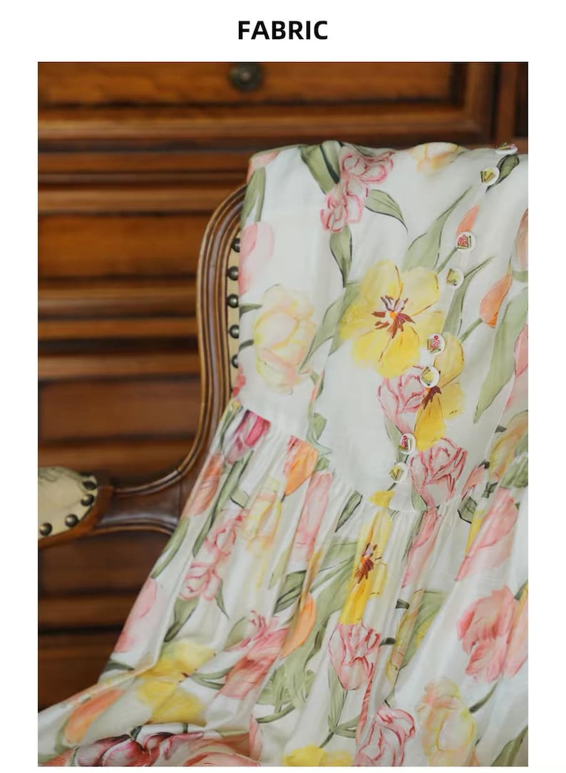 May include: White fabric featuring a watercolour floral design of yellow, pink, and orange tulips and green leaves. The fabric is draped over a wooden chair. The word "FABRIC" is at the top.