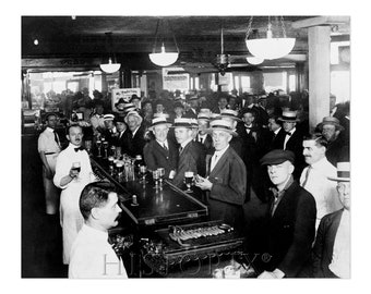 May include: A black and white photograph of a group of men in a bar, all wearing hats. The men are standing at the bar, drinking beer. There is a sign in the background that says "My Prediction".