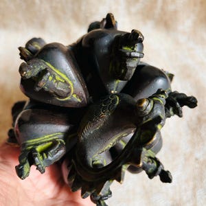 May include: A dark bronze sculpture of a mythical creature with multiple heads and a long tail. The sculpture is intricately detailed and has a green patina.