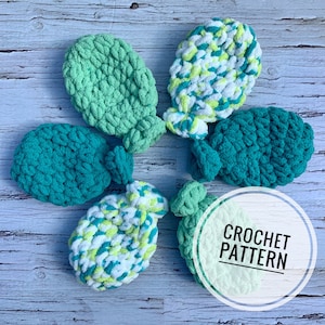 May include: Five crocheted fish toys in green, blue, and white. The fish are made with a fluffy yarn and have a knotted tail. The text "CROCHET PATTERN" is written on a white circle.