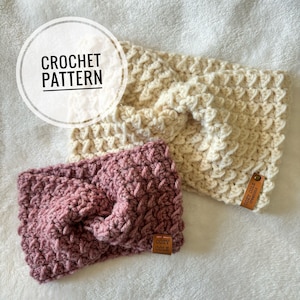 Pode incluir: Duas faixas de cabeça de crochê, uma em cor creme claro e outra em cor rosa escuro. Ambas as faixas têm um padrão texturizado e tecido e apresentam uma pequena etiqueta de couro com o texto "Cozy Cole" nelas.