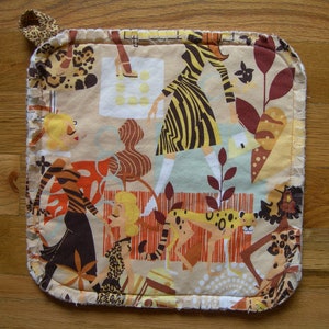 May include: A beige pot holder with a colorful pattern of women and animals. The pattern includes a woman in a zebra print dress, a woman in a tiger print dress, and a cheetah print animal.