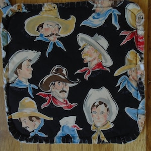 May include: Black and white pot holder with a repeating pattern of cowboys wearing hats. The cowboys are wearing different colored shirts and hats. The text "ECKEY", "HAL", "SLEAT", "SQUIAT", "SLIM", and "197" is visible on the pot holder.
