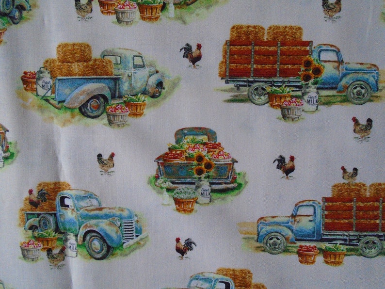 May include: A white background with a repeating pattern of blue vintage pickup trucks carrying hay bales, produce, and sunflowers. There are also roosters and chickens throughout the pattern.