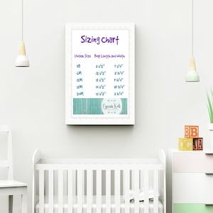 May include: A white framed sizing chart with a turquoise woodgrain background. The chart lists unisex sizes from newborn to 24 months with corresponding body length and width measurements in inches. The chart is titled "Sizing Chart" and includes the text "Cypress Kids Boutique".