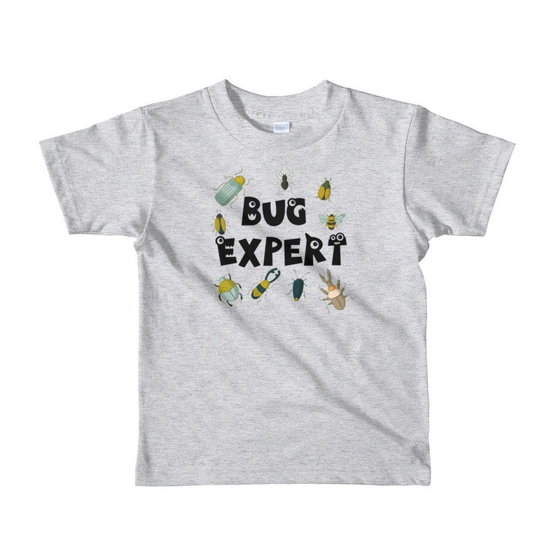 May include: A light gray t-shirt with a black circle design featuring the text "BUG EXPERT" surrounded by various cartoon bugs in shades of green, yellow, and brown.