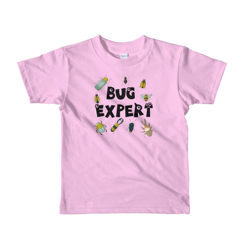 May include: Pink short-sleeved t-shirt with a black graphic of the text "BUG EXPERT" surrounded by cartoon bugs.
