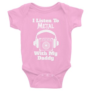 May include: Pink baby onesie with white text that reads "I Listen To METAL With My Daddy" and a graphic of a guitar amplifier with headphones.