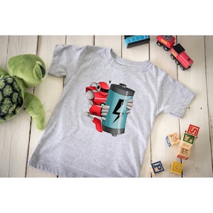 Pode incluir: Uma camiseta cinza com um robô vermelho segurando uma bateria azul com um raio.