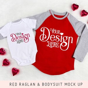 May include: A red raglan shirt and a white bodysuit with gray sleeves, both featuring the text "Your Design Here" in a decorative font. Red heart-shaped ornaments are scattered around the garments. The image is a mock-up.