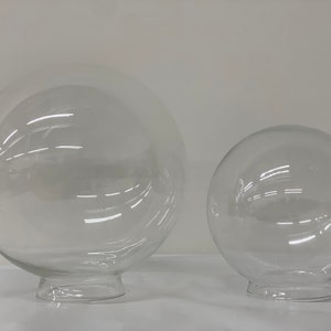 May include: Two clear glass globe light fixtures with a round base. The larger globe is about 10 inches in diameter and the smaller globe is about 6 inches in diameter.