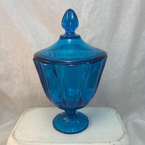 May include: A set of three ceramic mugs with a speckled, cream-colored glaze. Each mug features a different hand-painted floral design in shades of blue, green, and yellow. The mugs have a simple, rounded shape and a comfortable handle.