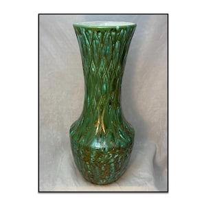 May include: A tall ceramic vase featuring a glossy emerald green glaze with brown undertones. The exterior surface is decorated with a repeating diamond pattern and vertical ridges that extend from the flared rim down to the rounded base.