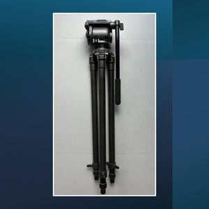 May include: A black tripod with three telescoping legs and a head for mounting a camera. The tripod has a handle for adjusting the camera angle and is designed for stability and support during photography or videography.