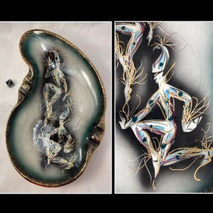 May include: A green and white ceramic ashtray with a stylized design of a figure in gold, blue, and black. The ashtray is shaped like a kidney bean.