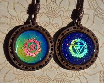 May include: Two wooden necklaces with colorful, glittery, resin pendants. One pendant features the Om symbol and the other features the fifth chakra symbol.