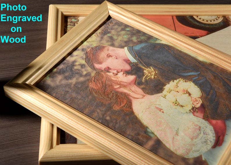 May include: A framed photo of a couple kissing, engraved on a wooden surface. The photo is in a light wood frame with a raised edge.
